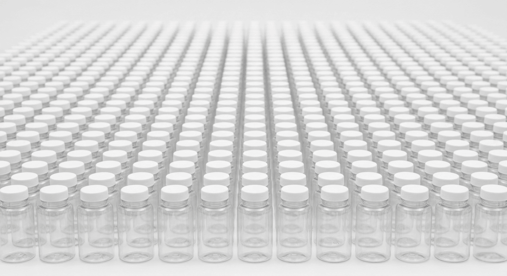 Rows of identical clear PET supplement bottles demonstrating high-volume stock packaging predictability.